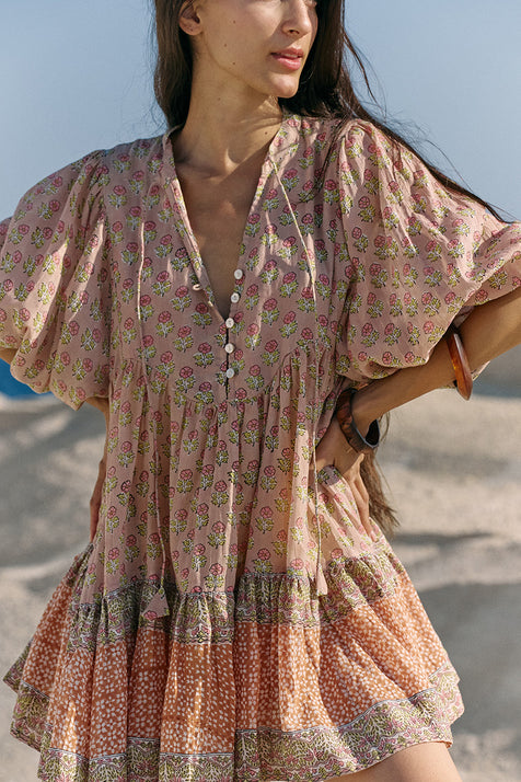 Close-up of woman wearing the Daughters of India Bhoomi Mini Dress in Sunset, showing the V-neckline with button detail and beautiful peach floral block print fabric